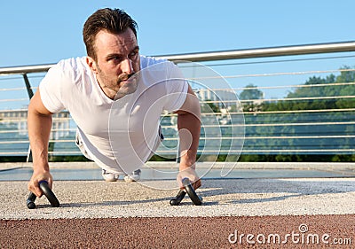 Close-up of a determined handsome middle aged man, athlete exercising outdoor, pumping muscles while performing push-ups training Stock Photo