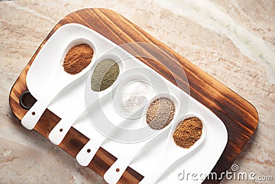 Close-up of Diverse of spices in white ceramic soup spoon over a wooden Top background. Stock Photo