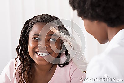 Doctor Applying Band Aid To Girl Head Stock Photo