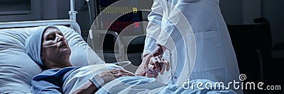 Close-up of a doctor checking pulse of his dying of cancer patient in the hospital Stock Photo