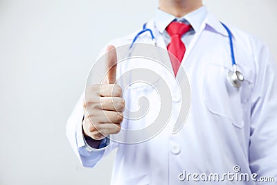 Close up of doctor in coat with stethoscope giving thumbs up in white isolated background Stock Photo