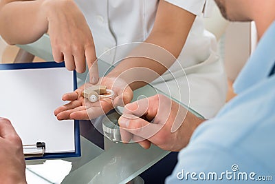 Close-up of doctor showing hearing aid to patient Stock Photo