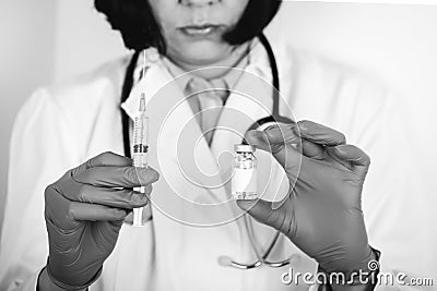 Close up of a doctor in white lab coat and sterile gloves holding syringe and medicine in ampoule Stock Photo