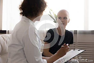 Close up doctor writing hairless woman complaints, filling patient card Stock Photo