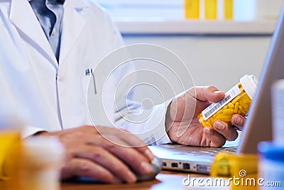 Doctor writing out prescription on a laptop Stock Photo