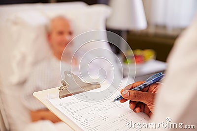 Close Up Of Doctor Writing On Senior Male Patient's Chart Stock Photo