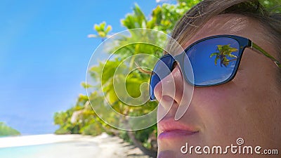 CLOSE UP: Detailed shot of reflection of a palm tree in girl's dark sunglasses. Stock Photo