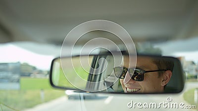 CLOSE UP, DOF: Young Caucasian male smiles while driving his car down the road. Stock Photo