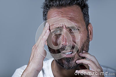 Close up dramatic portrait of young attractive anxious and depressed man in pain with hands on his head suffering headache and Stock Photo