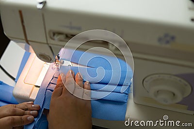 Dressmaker hands stitching surgical mask domestic production of health supplies. Healthcare, handwork, safety, Stock Photo