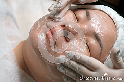 Close-up. East girl on the procedure of cleansing of the skin in the beauty salon. The hands of a professional beautician in glove Stock Photo