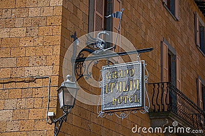 Close-up of elaborate Hotel plate, made of iron, stuck in stone wall and lamp in Orvieto. Editorial Stock Photo