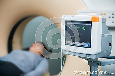 Close up electrocardiograph showing patient heart rate with pacient lying in computed tomography room. Selective focus Stock Photo