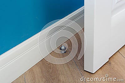 Close-up elements of the interior of the apartment. Metal chrome door stopper on laminate floor Stock Photo