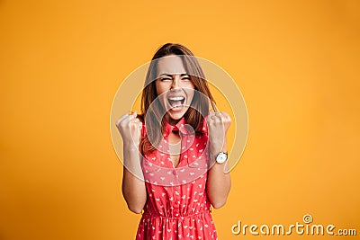 Close-up of emotional brunette woman keeping hands in fists, screaming while celebrating win Stock Photo