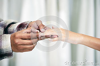 Groom hand holding bride hand and wear a wedding ring on bride ring finger Stock Photo