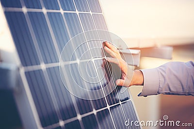 Close up of engineer hand is checking an operation of sun and cleanliness of photovoltaic solar panels on a sunset. Concept: Stock Photo