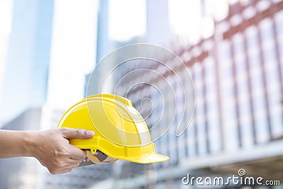 Close up of engineering male construction worker hand holding give safety yellow helmet for the safety of the work operation. Stock Photo