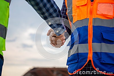 Close up of Engineers shaking hands at construction site, Construction worker in protective uniform shaking hands with businessman Stock Photo