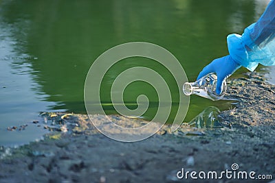 Close-up environmentalist hand of a researcher in a process of taking a sample of contaminated water from a lake Stock Photo