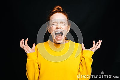 Close-up of excited angry young woman screaming with closed eyes on isolated black background. Stock Photo