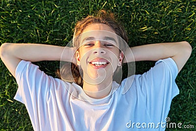 Close-up face of handsome guy 16, 17 years old on green grass, top view Stock Photo