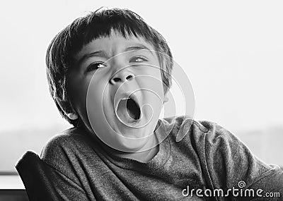 Close up face of Kid yawning lying , Sleepy child yawning and looking down, Black and white Indoor portrait tired child get a cold Stock Photo