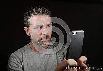 Young attractive and confident white man with blue eyes using online dating app or internet social media on mobile phone isolated Stock Photo