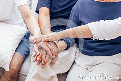 Close up of family with adult children and senior parents putting hands together sitting on sofa at home together. Family unity Stock Photo