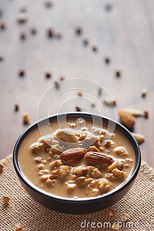 Close up of a famous Bengali dessert `Nolen Gurer Chanar Payesh` or Milk pudding of cottage cheese in a black bowl. Top-down view Stock Photo