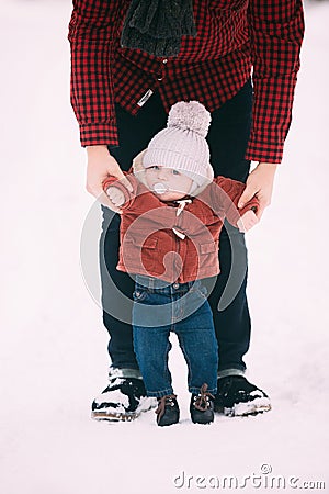 Close up.the father helps his son to take the first steps in snowy winter forest Stock Photo