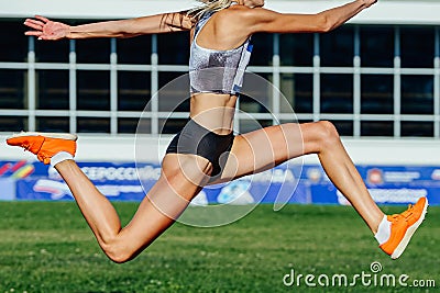 close-up female athlete jumping triple jump in summer athletics championships Stock Photo