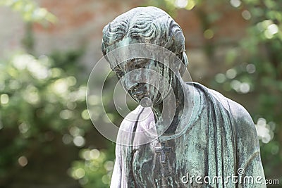 Close up of a female bronze statue of a woman with short hair with cross and cardigan in a park, Germany Stock Photo