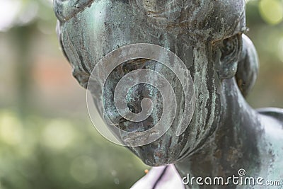 Close up of a female bronze statue of a woman with short hair with cross and cardigan in a park, Germany Stock Photo