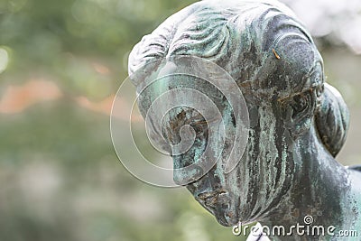 Close up of a female bronze statue of a woman with short hair with cross and cardigan in a park, Germany Stock Photo