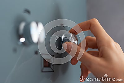 Close-up of female hand adjusting temperature of water heater. Modern home gas fired boiler. Stock Photo