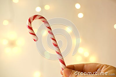 Close-up female hand holds candy cane, traditionally white with red stripes cane-shaped stick candy, Christmastide, Saint Nicholas Stock Photo