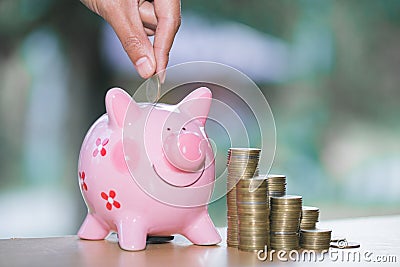 Close up female hand putting coin into piggy bank, save money for future Stock Photo