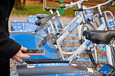 Young woman paying for bike rental with smartphone. Stock Photo