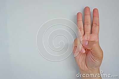 Close-up of female hand showing three fingers on grey background. Side view close up details. Stock Photo
