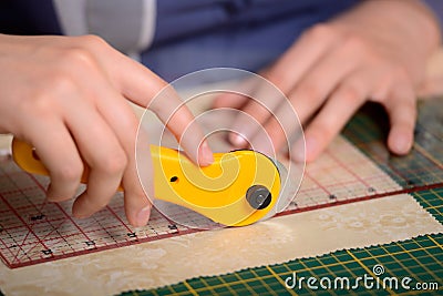 Close-up female hands cutting fabric with patchwork rotating cutter Stock Photo