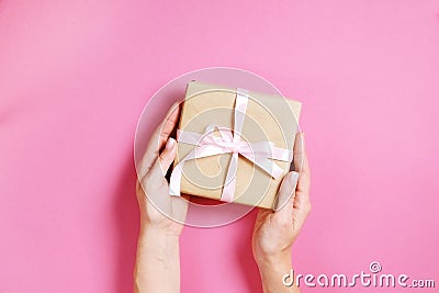 Close up of female hands holding birthday gift in vintage craft paper wrapping. Femenine composition with present in woman`s arms Stock Photo