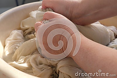 Close-up female hands of middle-aged woman wash at home in basin, pre-soak dirty sheets for washing, home chores concept, routine Stock Photo