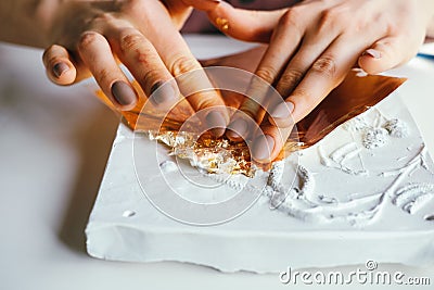 Close-up female hands working with plaster relief and golden foil Stock Photo