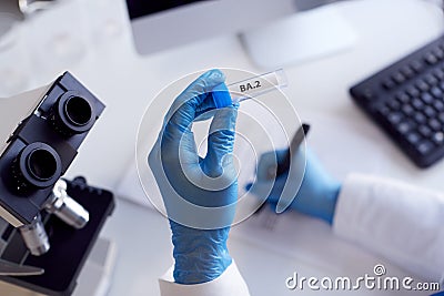 Close Up Of Female Lab Worker Wearing PPE Researching BA.2 Variant Of Covid-19 With Microscope Stock Photo