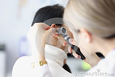 Close-up of female otolaryngologist examining ear with Stock Photo