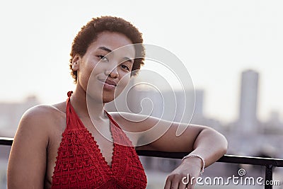 Close-up of female portrait of young adult attractive confident African. Charming darkskinned girl in red top stands against Stock Photo