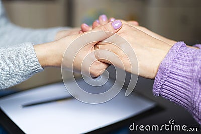 Close up of a female psychologist holding woman& x27;s hands during a therapy session. Stock Photo