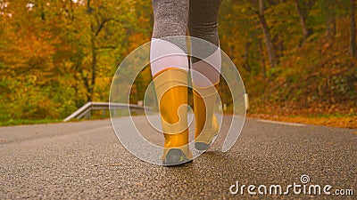 CLOSE UP: Female traveler wears rubber boots while walking down a forest route Stock Photo