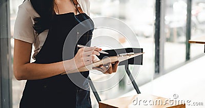 Close up female waitress take order cafe restaurant visitors couple, friendly professional woman server wear apron write Stock Photo